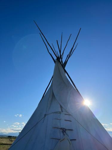 a close up of the tip of a tent with the sun at JMA Tipi in Riverton