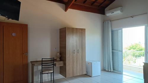 a room with a desk and a cabinet and a window at Pousada Mandala Botucatu in Botucatu