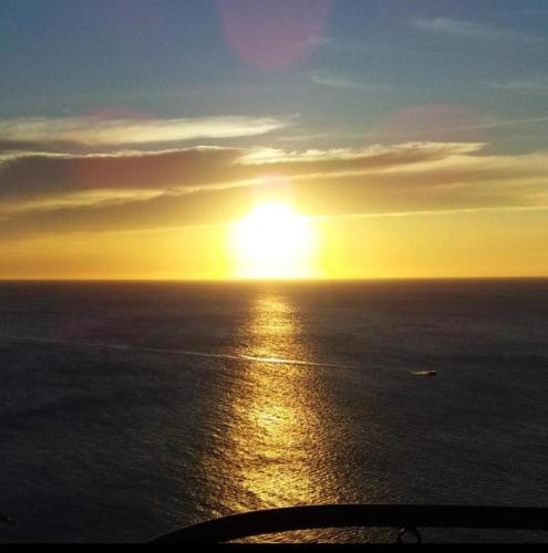 um pôr do sol sobre o oceano com um barco na água em El Peñon increible vistas al oceano Torre B em Santa Marta