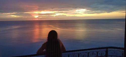 una mujer sentada en un balcón viendo la puesta de sol en El Peñon increible vistas al oceano Torre B, en Santa Marta