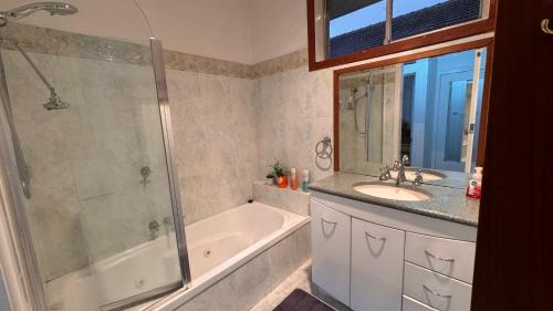 y baño con bañera, lavamanos y ducha. en luxury 5 bedrooms, Pool, Quiet, en Melbourne