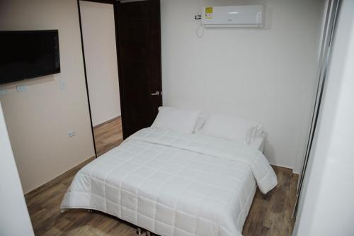 Cama blanca en habitación con espejo en Big Comfort Apartment en Valledupar