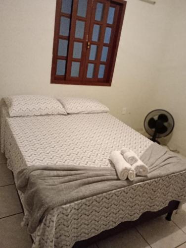 a bed with two rolled up towels on it at Suite canto do forte in Cabo Frio