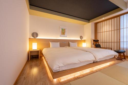 a bedroom with a large white bed with two lamps at Suminoyu in Yamanouchi