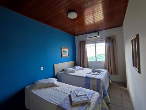 1 dormitorio con 2 camas y pared azul en Apartamento residencial solar dos Golfinhos - 204, en Florianópolis
