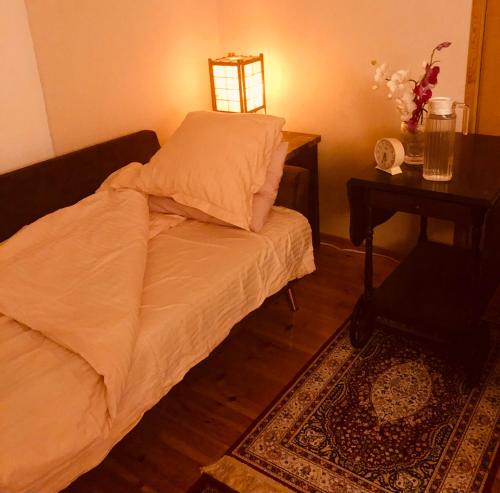 a small bed in a room with a table and a lamp at Meditation Room with light bfast - private toilet, no shower in Rovaniemi