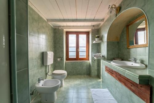 a green bathroom with two toilets and a sink at Antico Convento - Ospitalità Diffusa in Rocca Cilento