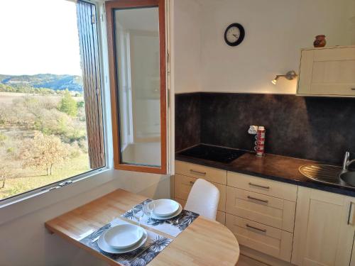 una pequeña cocina con mesa y ventana en Le panorama époustouflant " climatisé", en Gréoux-les-Bains