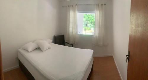 a white bed in a room with a window at Sítio - casa de campo in Domingos Martins