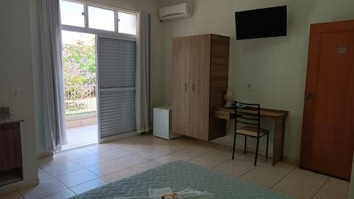 a living room with a table and a desk and a window at Pousada Mandala Botucatu in Botucatu