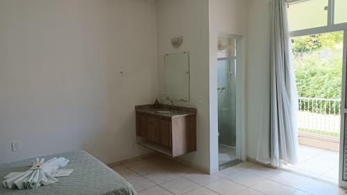 a bathroom with a sink and a shower with a mirror at Pousada Mandala Botucatu in Botucatu