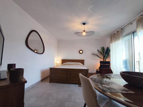 1 dormitorio con cama, mesa y espejo en Le panorama époustouflant " climatisé", en Gréoux-les-Bains
