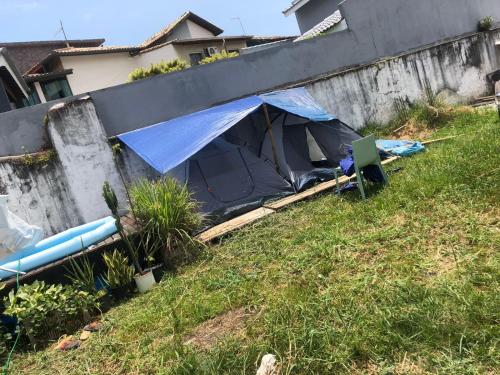 a tent in a yard next to a wall at Camping beira mar in Bertioga