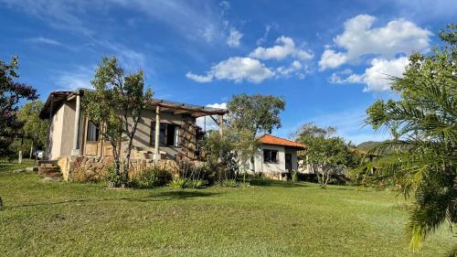 uma casa com um jardim de relva em frente em Pousada Sete Quedas em Carrancas