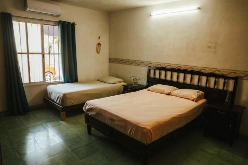a bedroom with two beds and a window at Hostal Casa Cucu - Wifi, Hot Water, AC, free water refill - Stay 3 nights or more and get 1 day free bikes & 1 free laundry wash in Valladolid