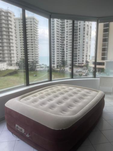 a large bed in a room with windows at Habitación Frente a la Bahia con baño privado in Panama City