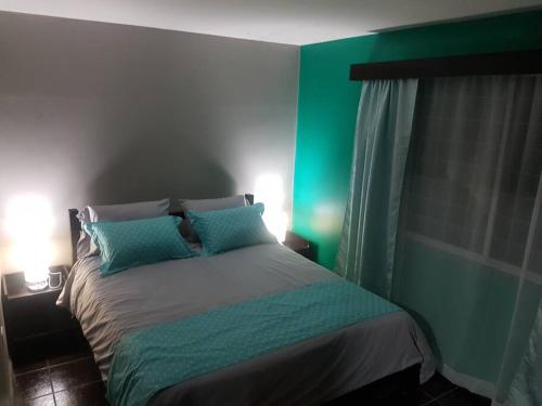 a green bedroom with a bed with two pillows at El Descanso in Cuenca