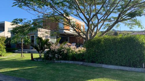 a house with a tree in a yard at Getaway Bach Whangapoua in Coromandel Town