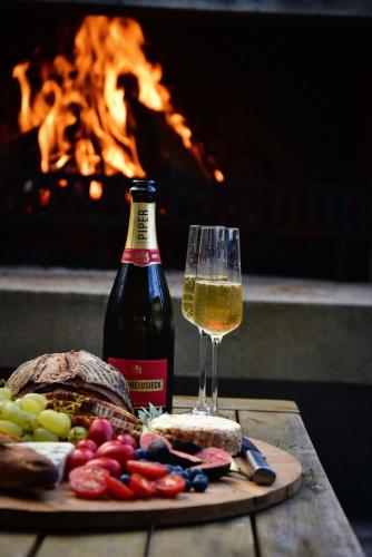 a glass of wine and a plate of food and a bottle at Getaway Bach Whangapoua in Coromandel Town