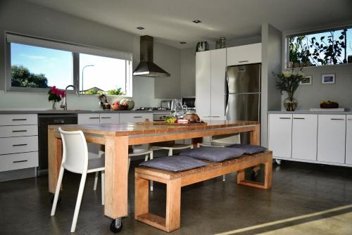 a kitchen with a wooden table and white cabinets at Getaway Bach Whangapoua in Coromandel Town