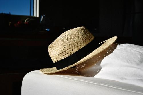 a straw hat sitting on top of a bed at Getaway Bach Whangapoua in Coromandel Town
