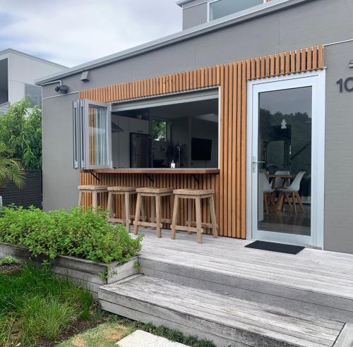 a small house with a deck with a patio at Getaway Bach Whangapoua in Coromandel Town