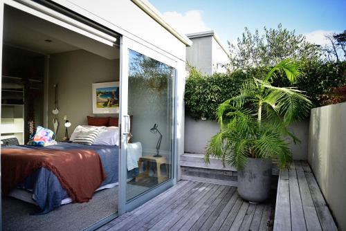 a bedroom with a bed on a deck with a sliding glass door at Getaway Bach Whangapoua in Coromandel Town