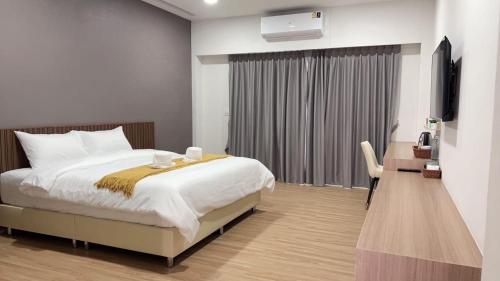 ein Hotelzimmer mit einem Bett und einem TV in der Unterkunft ดิ อัยย์ชญา โฮเทล in Ban Phraek Sa