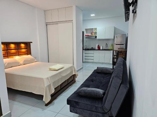 a bedroom with a bed and a couch and a kitchen at Monoambiente en Condominio Boulevard in Trinidad