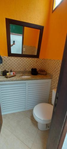 ein Badezimmer mit Toilette, Waschbecken und Spiegel in der Unterkunft Casa Canto Verde Camburi in Camburi