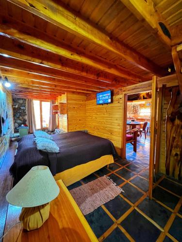 a bedroom with a large bed in a log cabin at Cabañas Casa de Piedra in Trevelín