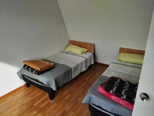 2 Betten in einem kleinen Zimmer mit Holzböden in der Unterkunft Costa Margarita in El Tabo