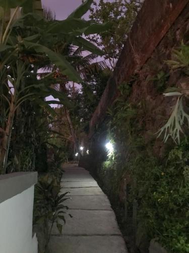 a walkway in a garden at night with lights at Heri house ubud in Ubud