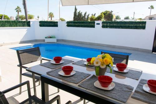 una mesa con flores junto a una piscina en CASA SOLEADA. Intimidad, piscina y mucho sol., en Santiago de la Ribera