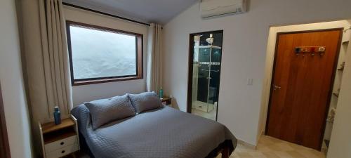 a small bedroom with a bed and a window at Casa Canto Verde Camburi in Camburi