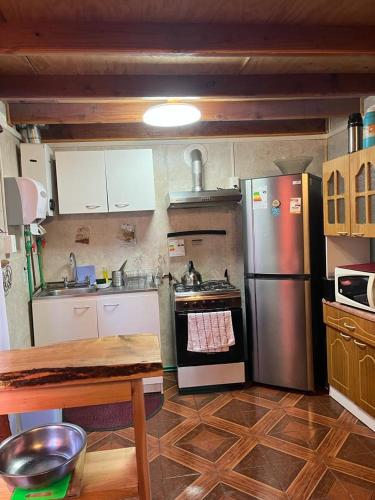 uma cozinha com um fogão, um frigorífico e uma mesa em cabaña norma cerro castillo em Villa Cerro Castillo