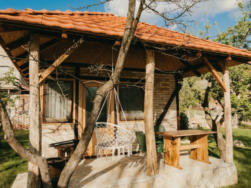 a wooden pavilion with a table and a bench at Drinska Dedovina in Gornja Trešnjica