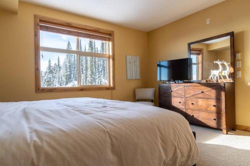 a bedroom with a bed and a dresser with a mirror at The Aspens 5 w/ Hot Tub in Big White