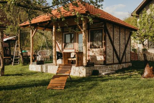 a small cabin with a staircase in the grass at Drinska Dedovina in Gornja Trešnjica
