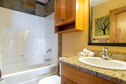 a bathroom with a sink and a tub and a toilet at The Aspens 5 w/ Hot Tub in Big White