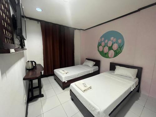 a room with two beds and a table and a tv at Casa De Soledad Vigan City in Vigan