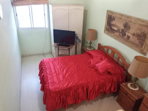 1 dormitorio con cama roja y TV en Sai Ram en San Martín