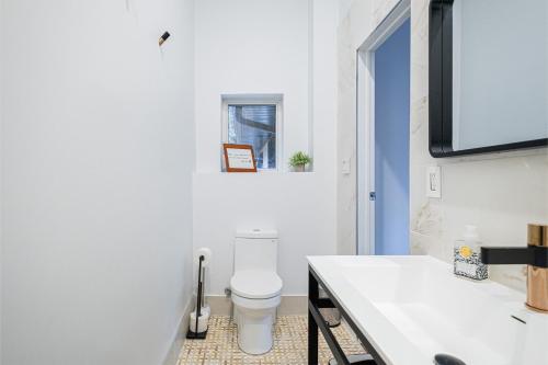 a white bathroom with a toilet and a sink at Queen Loft in Nature in Toronto
