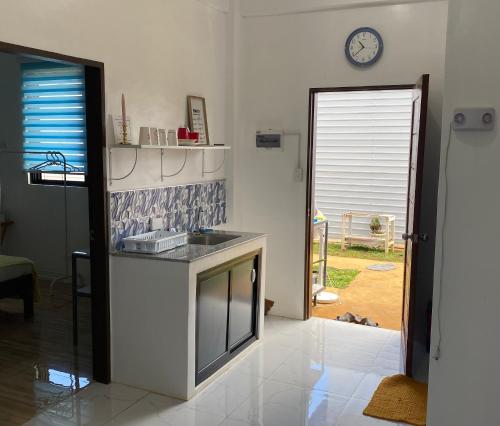 a kitchen with a sink and a clock on the wall at Concetta Inn in Manolo Fortich