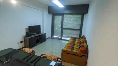 Habitación con 1 dormitorio con mesa y TV. en Departamento Ñandú - 2 ambientes zona Güemes en Mar del Plata