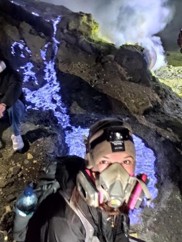 a man wearing a gas mask in front of a waterfall at Dannu's Homestay Ijen and Bromo Tour in Banyuwangi