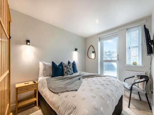 a bedroom with a bed with blue pillows and a window at Sea Breeze in Torquay