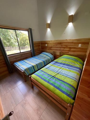 two beds in a room with a window at Cabaña Rústica - Sector Pichares in Pichare