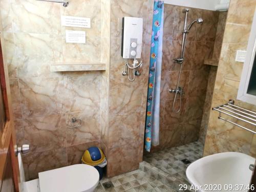 y baño con ducha, aseo y lavamanos. en Tropicasa Siquijor Seafront Guest House en Solangon