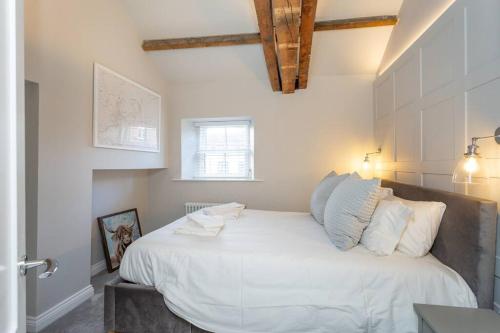 um quarto com uma cama grande com lençóis brancos e almofadas em The Old Vet’s House em Masham